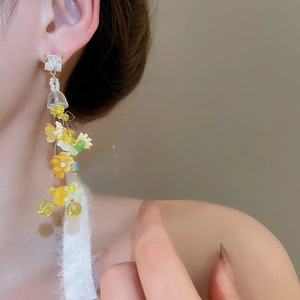 Detail of flower tassel earring with yellow petals and transparent crystal beads