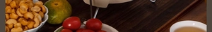 Close-up of golden crispy snacks served with fresh lime and cherry tomatoes on a dark wood table