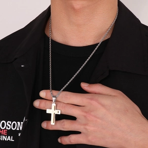 Macro detail of a two-tone gold and silver layered cross pendant on a twist rope chain
