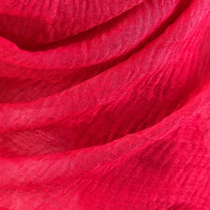 Macro shot of red pleated cotton linen fabric texture with soft natural fringed edges