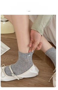 Close-up showing the high elasticity of gray mesh socks with white ribbon bows