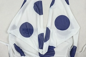 Detail of white mesh fabric with blue polka dots and visible stitching on the dress