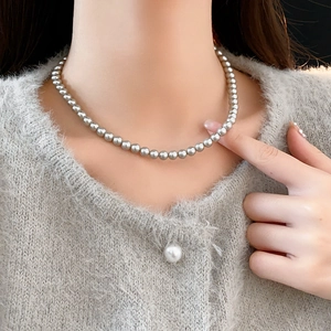 Detail showing elegant silver gray pearl necklace layered on a soft gray sweater