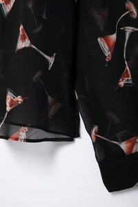 Détail du tissu en mousseline noire avec motifs cocktails rouges et cerises sur la manche