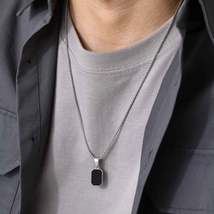 Close-up of men's minimalist silver chain with a black rectangular pendant on a model