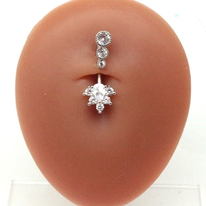 Detail view of silver heart-shaped belly button ring with zircon wings on a model