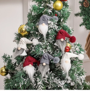 Close-up of Nordic gnome bells with knitted hats hanging on a snowy Christmas tree