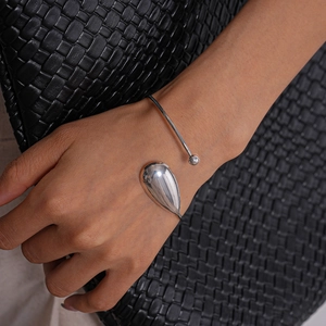 Polished silver teardrop cuff bracelet with asymmetrical open design on a wrist