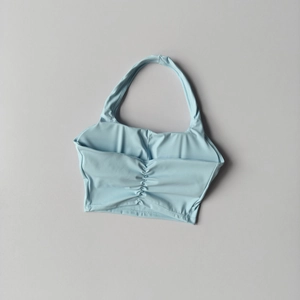 Detail of ruched center and halter neck design on a light blue sports bra top