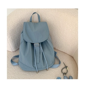 Detail of blue nylon drawstring backpack on white textured background with flap cover