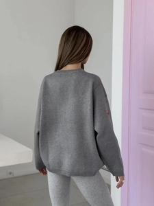 Detail view of the back of a grey knit sweater featuring a relaxed fit and long sleeves