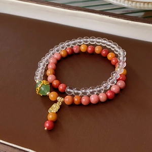 Detail of colorful crystal fluorite beads with a gold lucky charm on a layered bracelet