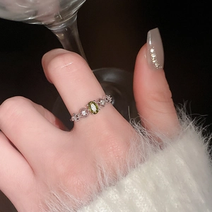 Close-up of vintage silver ring with oval green gemstone and diamond detailing on finger