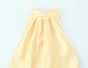 Détail de la texture satinée jaune brillant et de l'encolure drapée de la robe longue