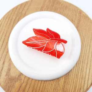 Detailed view of leaf-shaped red acetate hair claw clip with white marble vein patterns