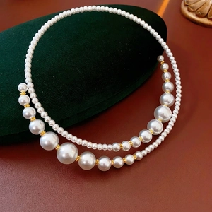 Irregular double-layer pearl necklace with golden floral accents on velvet pouch