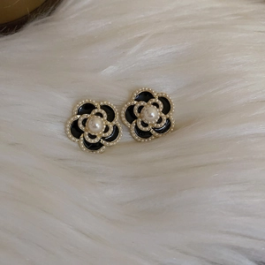 Detail view of French retro camellia earrings with black enamel and white pearls