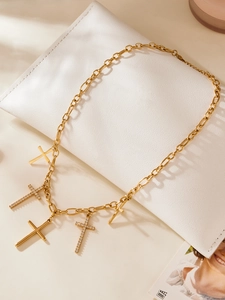 Détail du collier pendentif croix doré avec incrustations de zircons sur cuir blanc