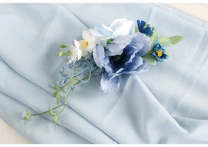 Macro shot of sky blue silk flower with delicate leaves for wedding attire decoration