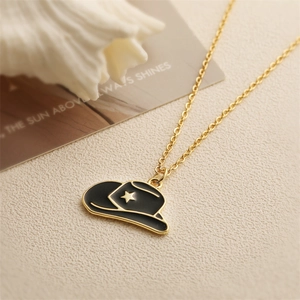 Collier avec pendentif chapeau de cowboy doré et émail noir avec étoile sur fond beige