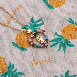 Macro shot of gold heart pendant with Virgin Mary relief and colorful gemstones