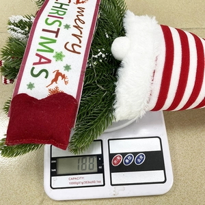 Close-up of a 188g Christmas wreath with green pine needles and red striped Santa hat