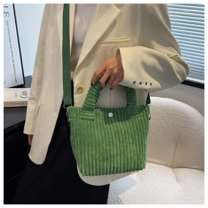 Close-up of green corduroy bucket bag with striped texture shown on person