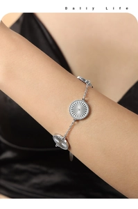 Detailed view of titanium steel gold bracelet with sunburst engraved round charms