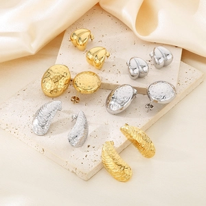 Close-up of geometric gold and silver stainless steel earrings on a stone tray