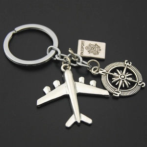Macro detail of silver travel keychain with airplane, passport and compass charms
