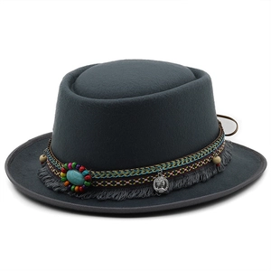 Close-up of charcoal felt hat featuring ethnic tassels, beads and vintage coin pendant