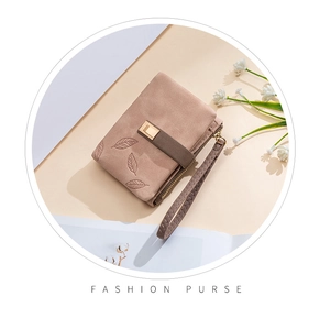 Detail of a dusty pink matte wallet with leaf embossing, zip closure and handle strap