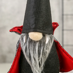Close-up of vampire gnome ornament with black felt hat, red cape, and white sharp fangs