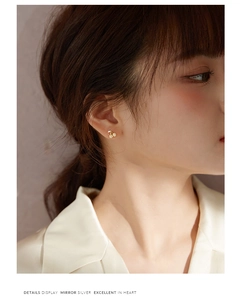 Macro detail display of cherry shaped silver gold plated stud earrings on a female model