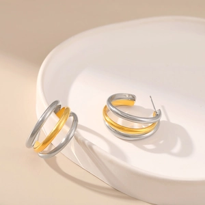 Three-layer C-shaped mixed gold and silver matte stud earrings on a ceramic tray