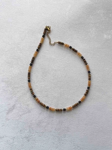 Detail of bohemian handmade beaded necklace with brown and orange beads and gold clasp