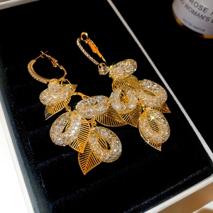 Close-up of golden leaf tassel earrings with sparkling zircons on a black jewelry box
