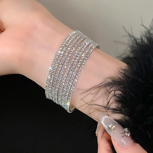 Macro-opname van een sprankelende meerrijige strass armband om de pols met zwarte veren cuff