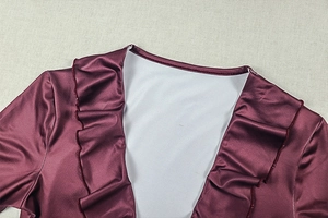 Close-up of elegant burgundy satin dress featuring a deep V-neck with ruffled trim details