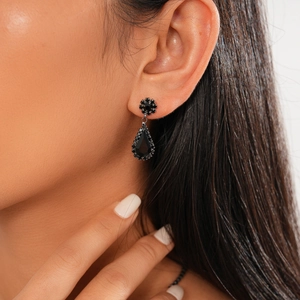 Detailed view of black teardrop earrings with crystals worn by a female model