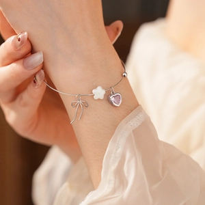 Detailed close-up of a silver bow and purple heart gemstone charm on the stylish bracelet