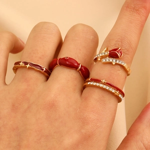 Detail of four-piece gold ring set featuring red rose enamel and zircon pavé accents