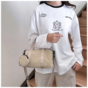 Beige nylon cylinder crossbody bag with round pouch shown on model in urban staircase setting