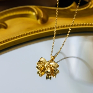 Elegant gold bow pendant necklace on mirror surface with vintage frame background