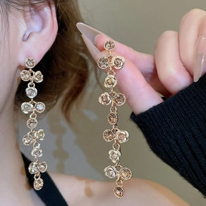 Detail of long drop earrings featuring cream rose petals and sparkling light brown rhinestones
