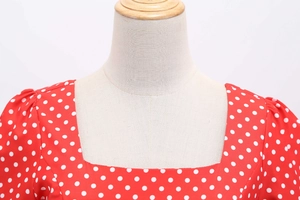 Detail of square neckline on red polka dot dress showing fabric texture and seams