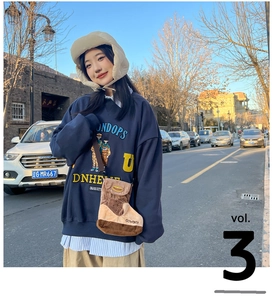 Detail of navy blue hoodie with yellow 3D embroidery and cute brown boot-shaped crossbody bag