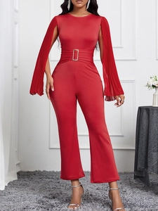 Elegant red jumpsuit with long pleated sleeves and a golden buckle belt in a studio setting