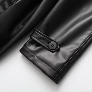 Detailed close-up of black leather coat cuff with button and textured sleeve detail