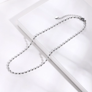 Macro view of silver titanium steel bead necklace featuring oval beads and lobster clasp